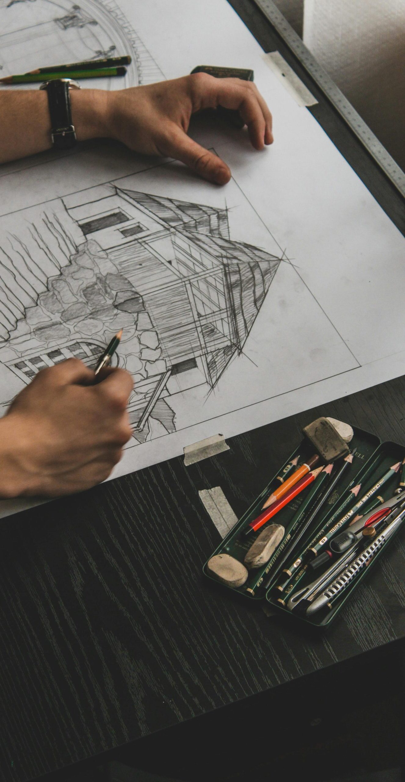 Architect sketching building plans with pencils on a desk, showcasing creative design process.