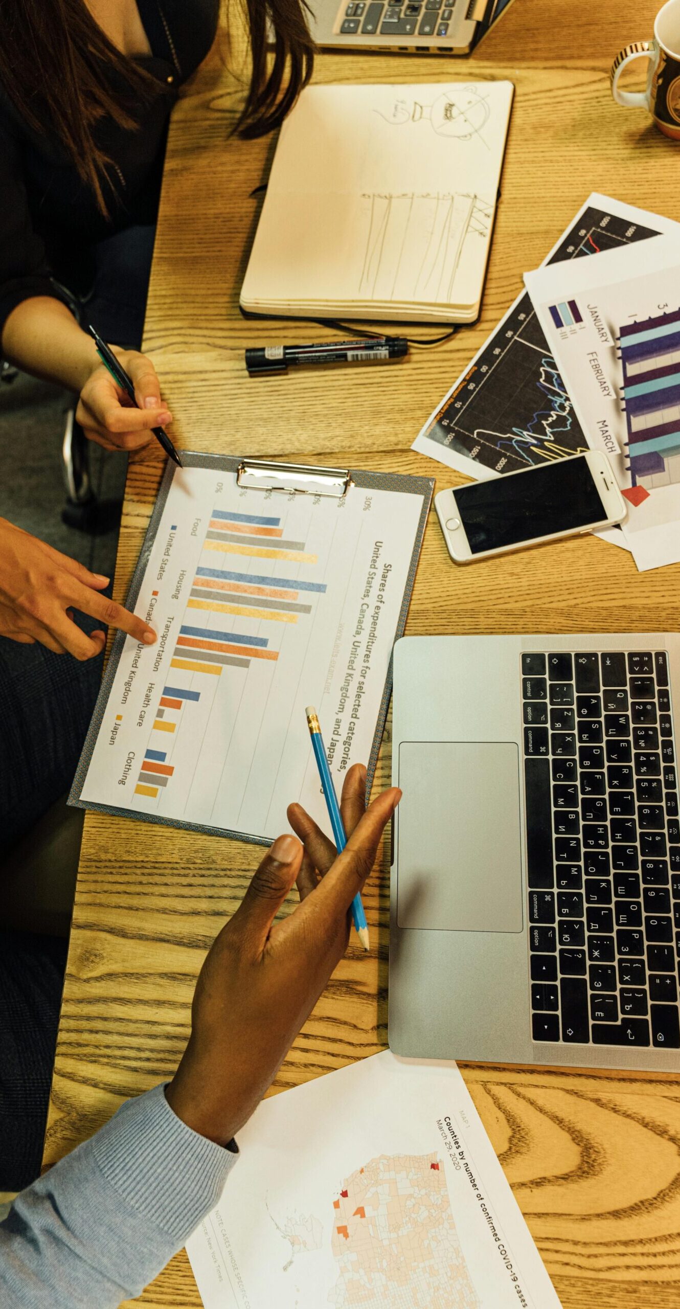 Team members analyzing business charts and reports in an office setting around a wooden table.