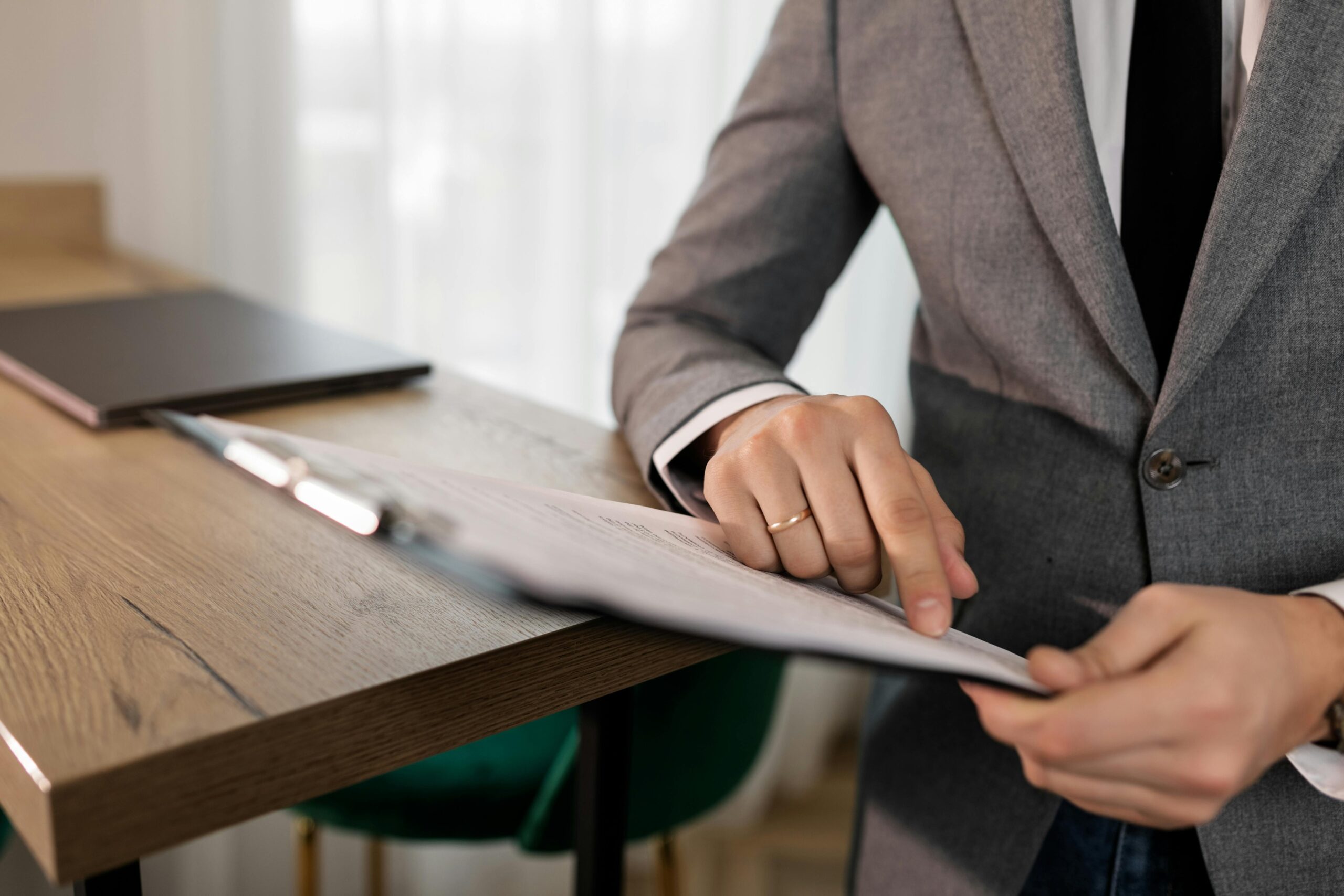 Professional businessman in suit reviewing documents on clipboard at office desk.
